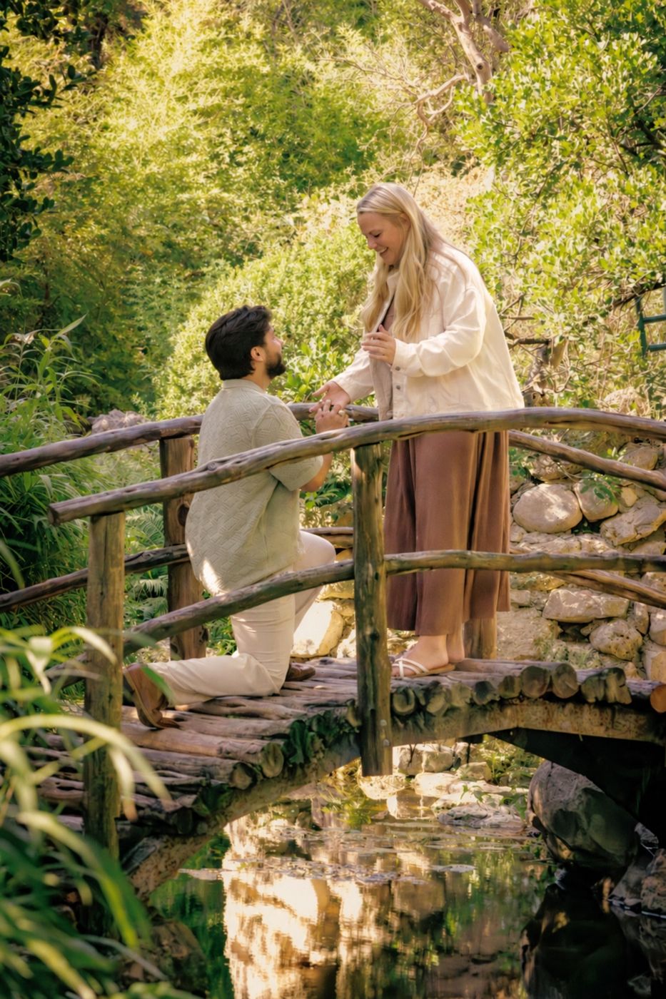 Alan on one knee proposing to Hailey on a wooden bridge